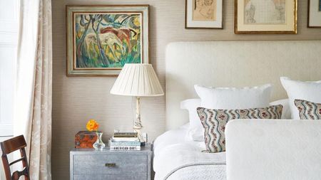 A bed with a beige fabric headboard and metallic bedside drawers 