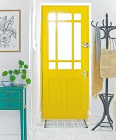 A white hallway with a yellow front door and a patterned indoor doormat