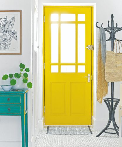 A white hallway with a yellow front door and a patterned indoor doormat