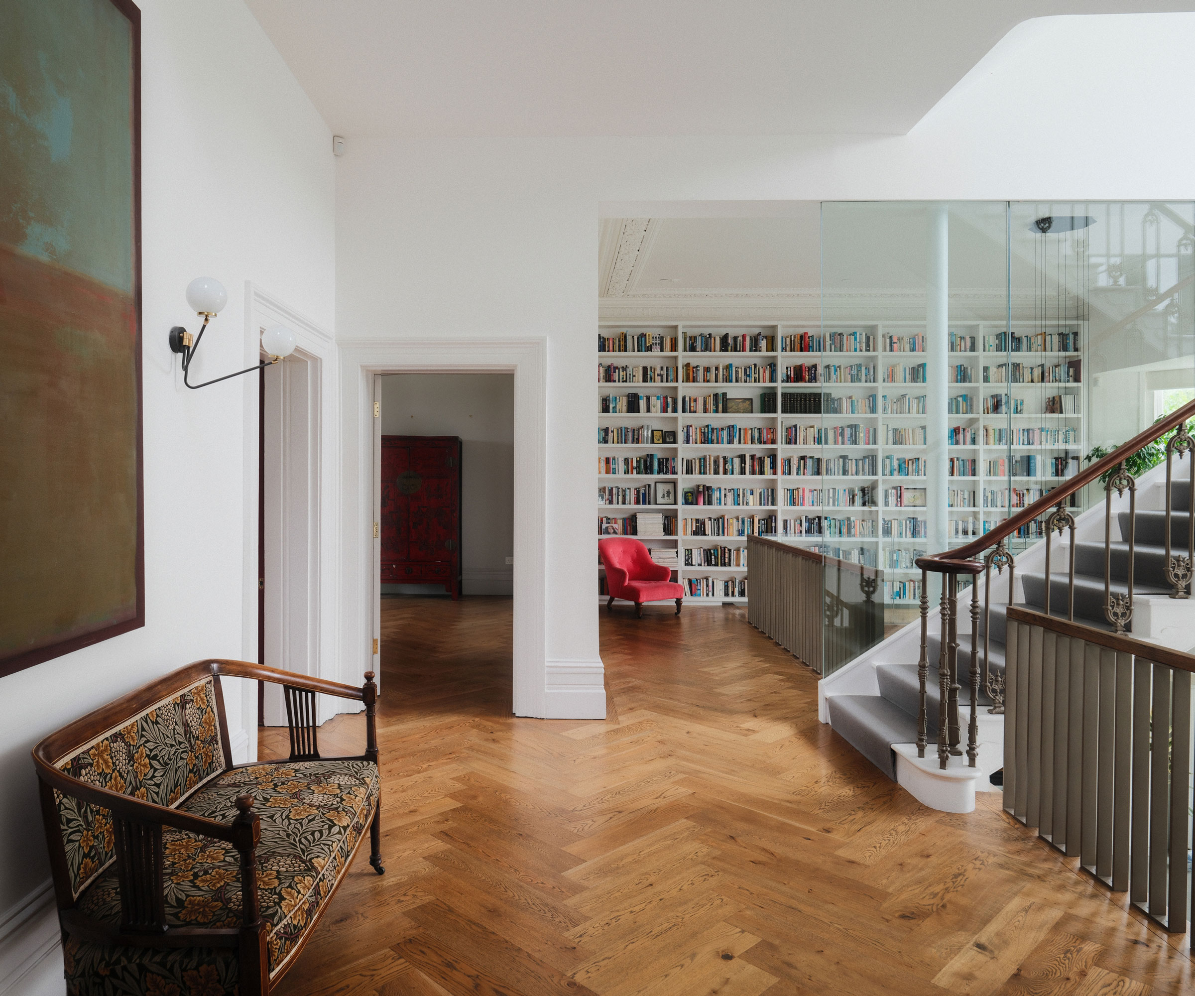 landing with wooden herringbone flooring and wall book storage