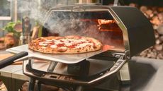 Ooni Karu 2 Pro with a fresh pizza being taken out of it on a metal pizza peel. 