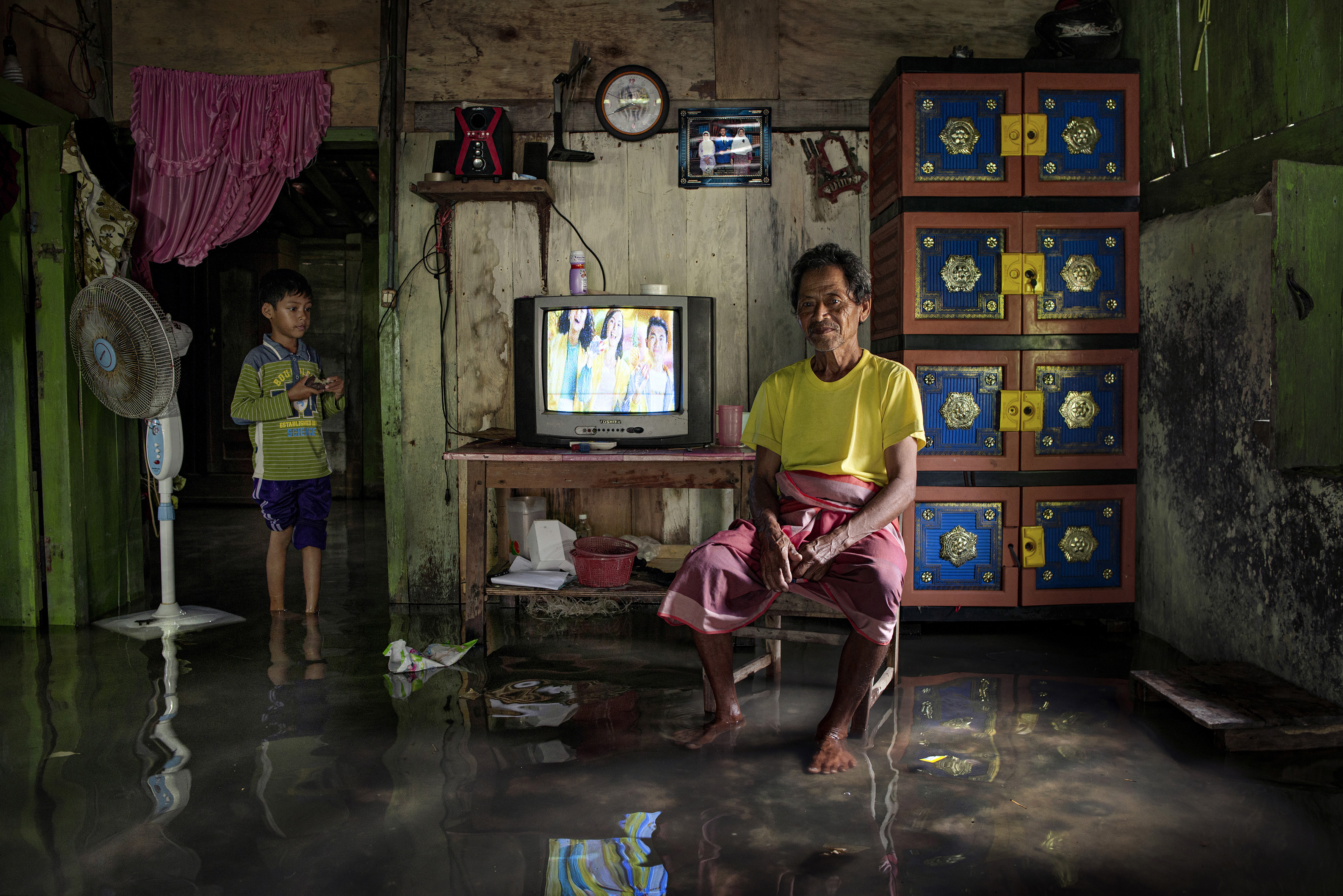 A person and a child standing in a flooded home room.