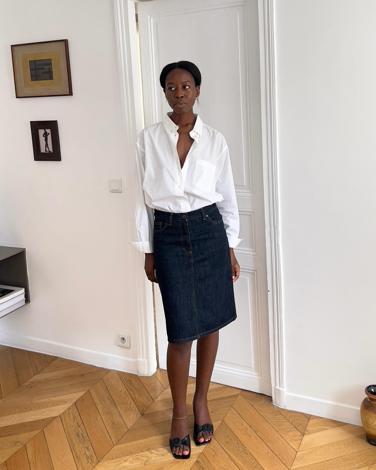 Sylvie Mus wearing a white button-down shirt and denim pencil skirt.