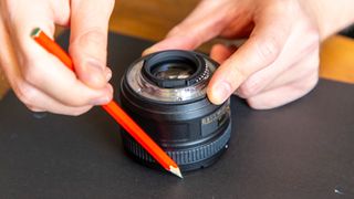 Hands drawing around lens with a pencil