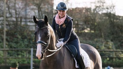 Dressage rider Louise Bell pats her rising star dressage horse Peaky Blinder on the neck as they both look at the camera during a magazine shoot at home