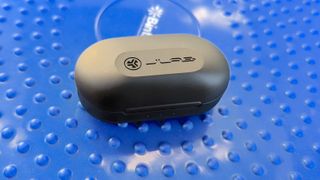The JLab JBuds Air Pro charging case resting on a workout stabilizer cushion