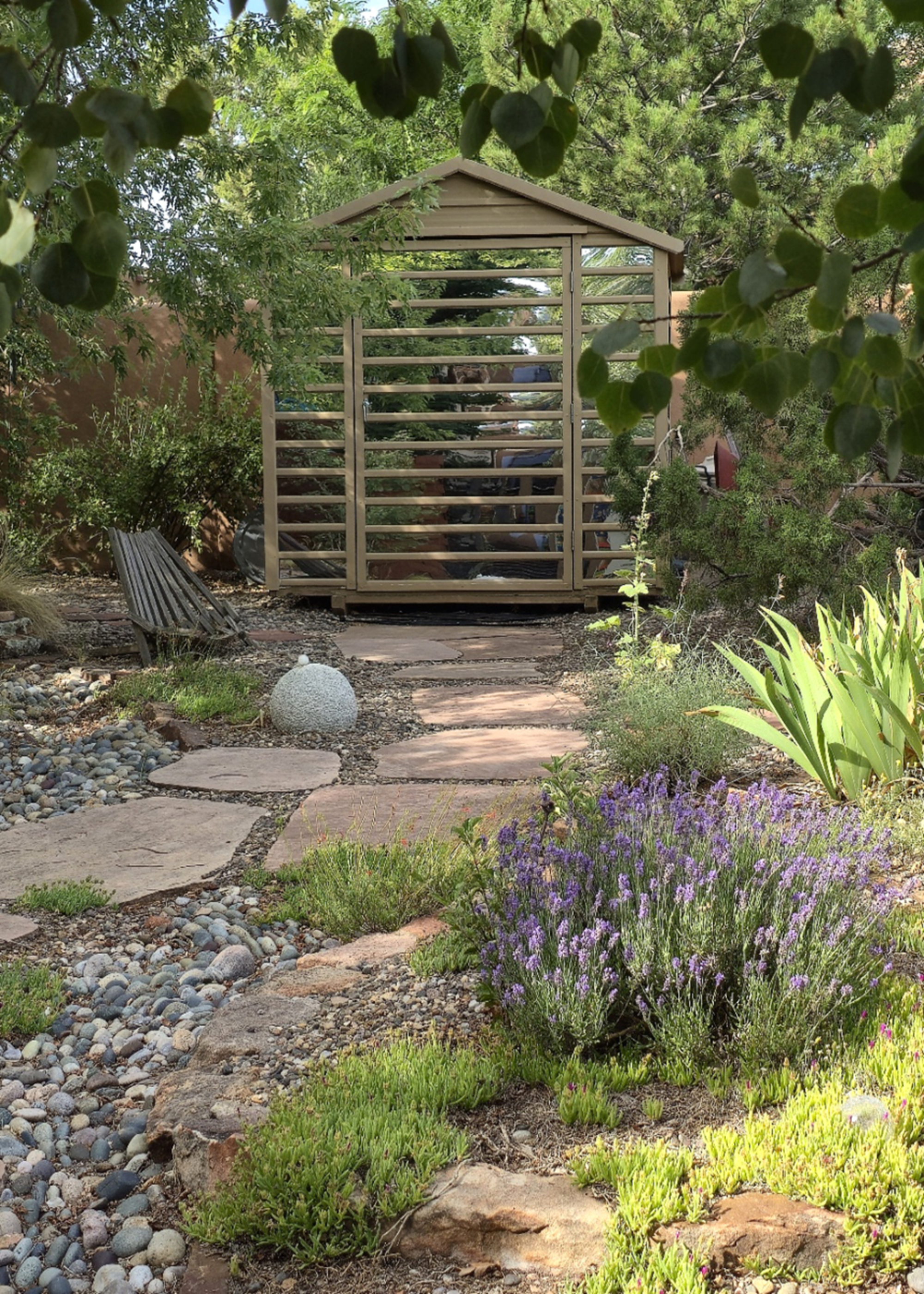 A shed covered with mirrored panels at the end of a garden path