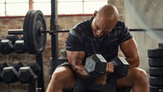 Muscular person curling a dumbell in a gym