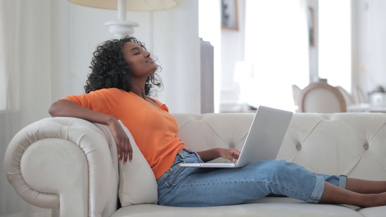 Best portable air conditioner 2022, image shows woman lying on a couch with laptop on her lap