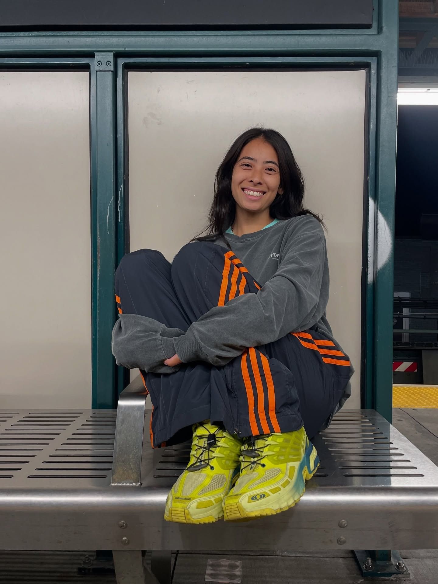 Influencer wearing track pants with a longsleeve tee and neon yellow sneakers