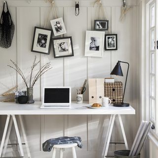 room with frames on wall and laptop on table
