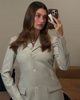 Hailey Bieber poses in front of her mirror wearing a vintage gray blazer