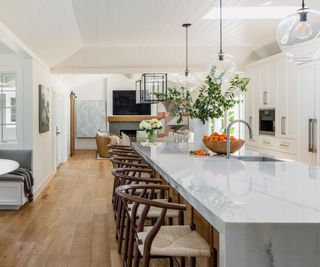 White kitchen with large kitchen island with marble top
