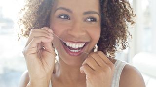 How to floss your teeth: image shows woman flossing teeth