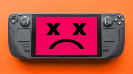 A Steam Deck displaying a red screen with two X-ed out eyes and a frown. 