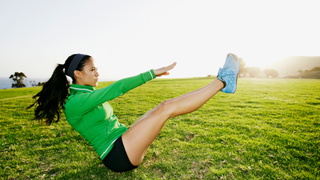 A woman performing a v sit up outside