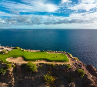 Golfers play on the course of Villa del Palmar on the Loreto Islands above the dark blue ocean