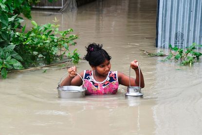 A girl in India wades through flood waters.