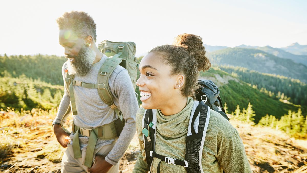 Smiling daughter and father on backpacking trip on fall afternoon