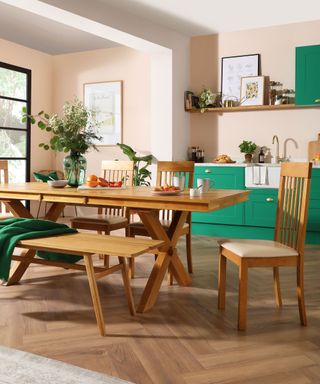 bright green kitchen with herringbone wood flooring and wooden dining table and chairs