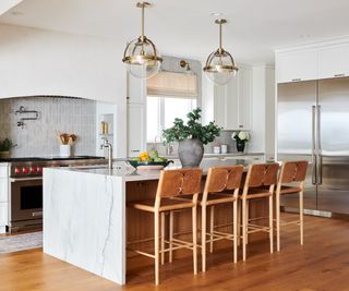 White modern kitchen island with wooden bar stools in kitchen with hardwood floors