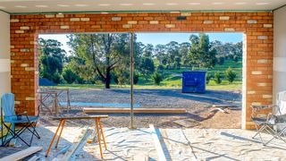 Inside a double door garage conversion showing plasterboard and tools looking onto a large outdoor space