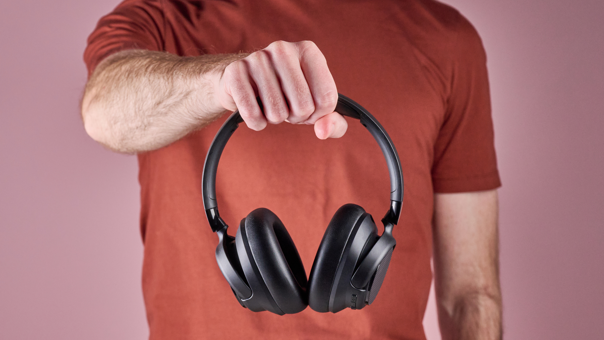 Amazon Basics Hybrid Active Noise Cancelling Headphones held in a man's hand
