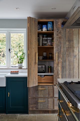 wooden pantry cabinet in blue kitchen