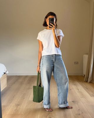 Woman wears white t-shirt, blue jeans and snake print heels