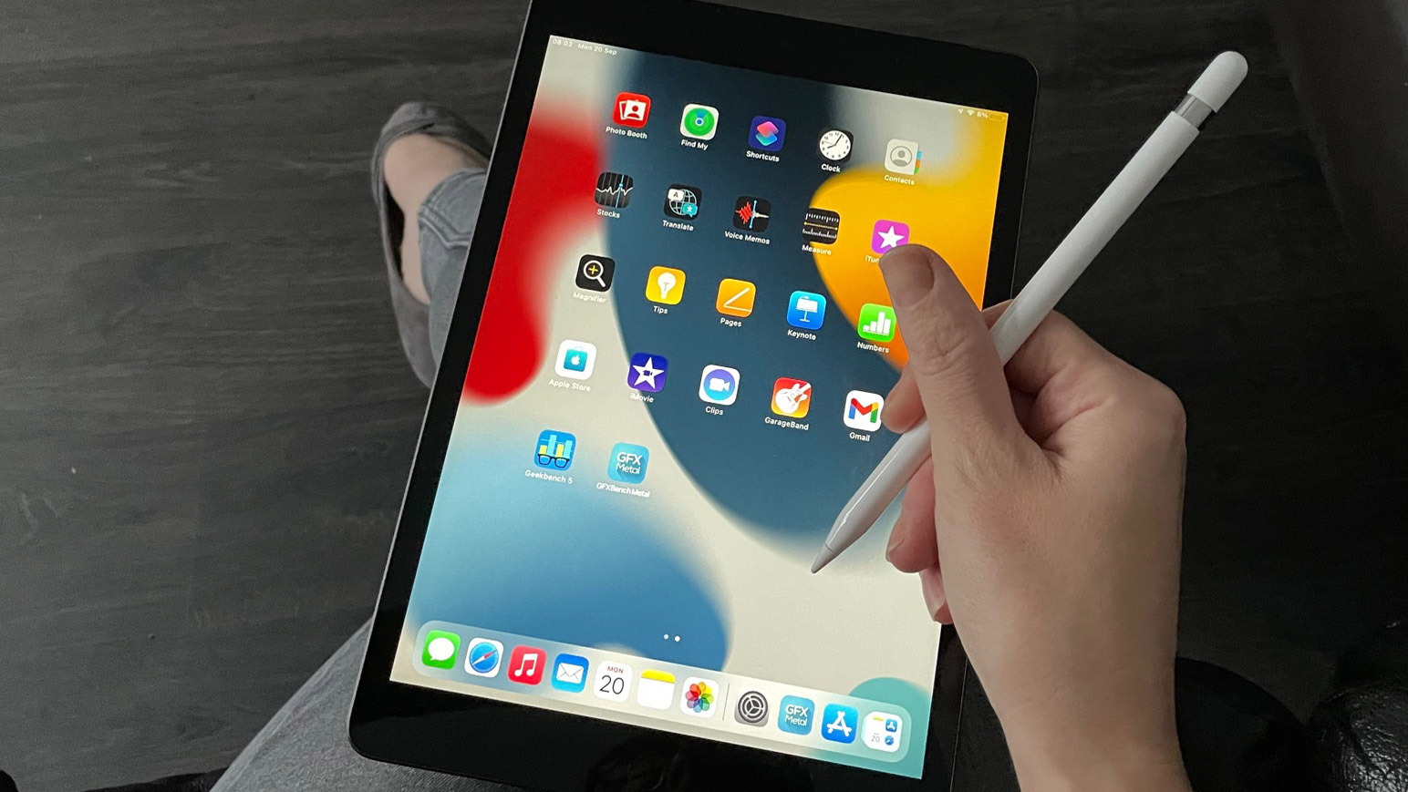 Apple iPad 10.2 (2021) - en person sidder med tabletten på knæet og har en pen i hånden.