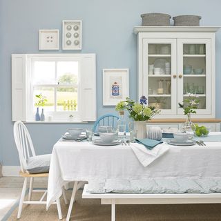 dining room with wall mounted kitchen shelf blue wall and white table