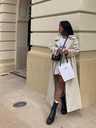 woman wearing chelsea boot wearing mini skirt with t-shirt and trench coat