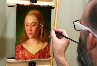An artist painting a portrait in oils and adding detail