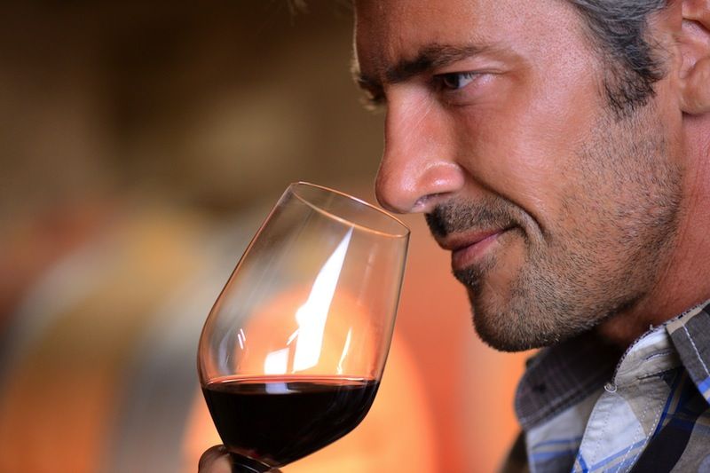 A man smells a glass of wine before tasting it.