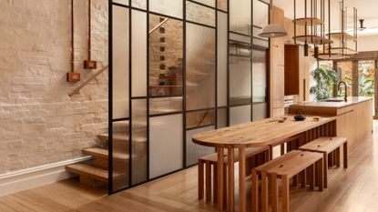 A bright and airy open concept dining room and kitchen drenched in wood and a stained glass wall by a staircase