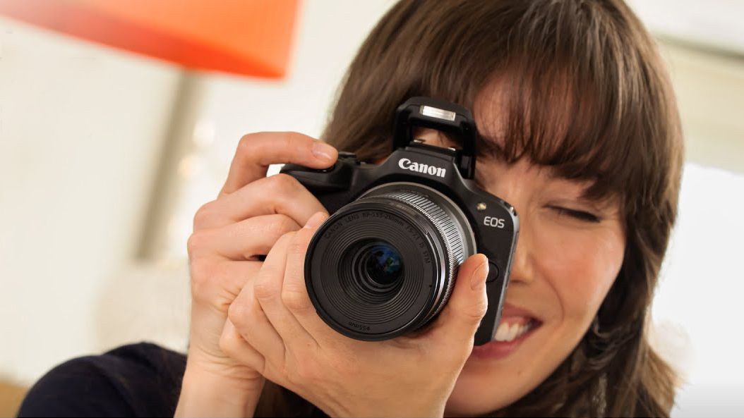 Woman holding a Canon EOS R100 camera