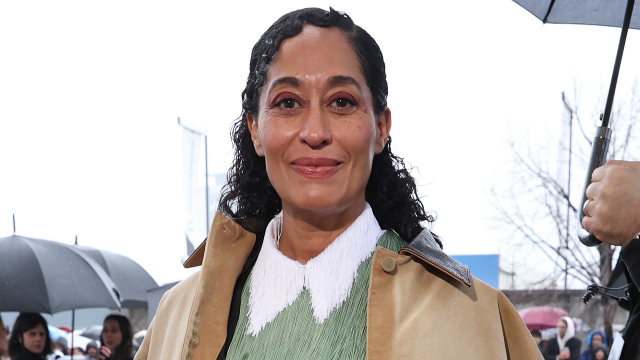 Tracee Ellis Ross wearing a utility style coat, a fringe top, and a semi-sheer midi skirt