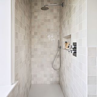 shower with neutral stone tiles and niche shelving