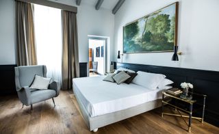 Bedroom with wooden flooring, dark panelling on the walls and a large piece of artwork