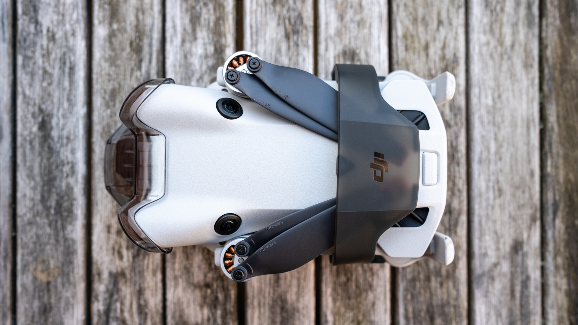 DJI Mini 4 Pro folded with its propeller strap on a wooden table