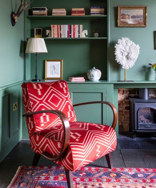 living room with green walls and a red upholstered arm chair and a red patterned rug