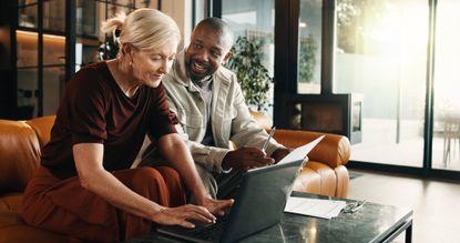 Mature couple, laptop and smile with paperwork in home for mortgage, bills or investment. Mature man, woman and document with tech for financial planning, budget expenses or invoices together