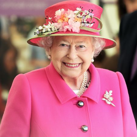 Queen Elizabeth wears a bright pink coat and matching hat adorned with flowers