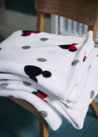 room with wooden chair and printed mickey mouse towels