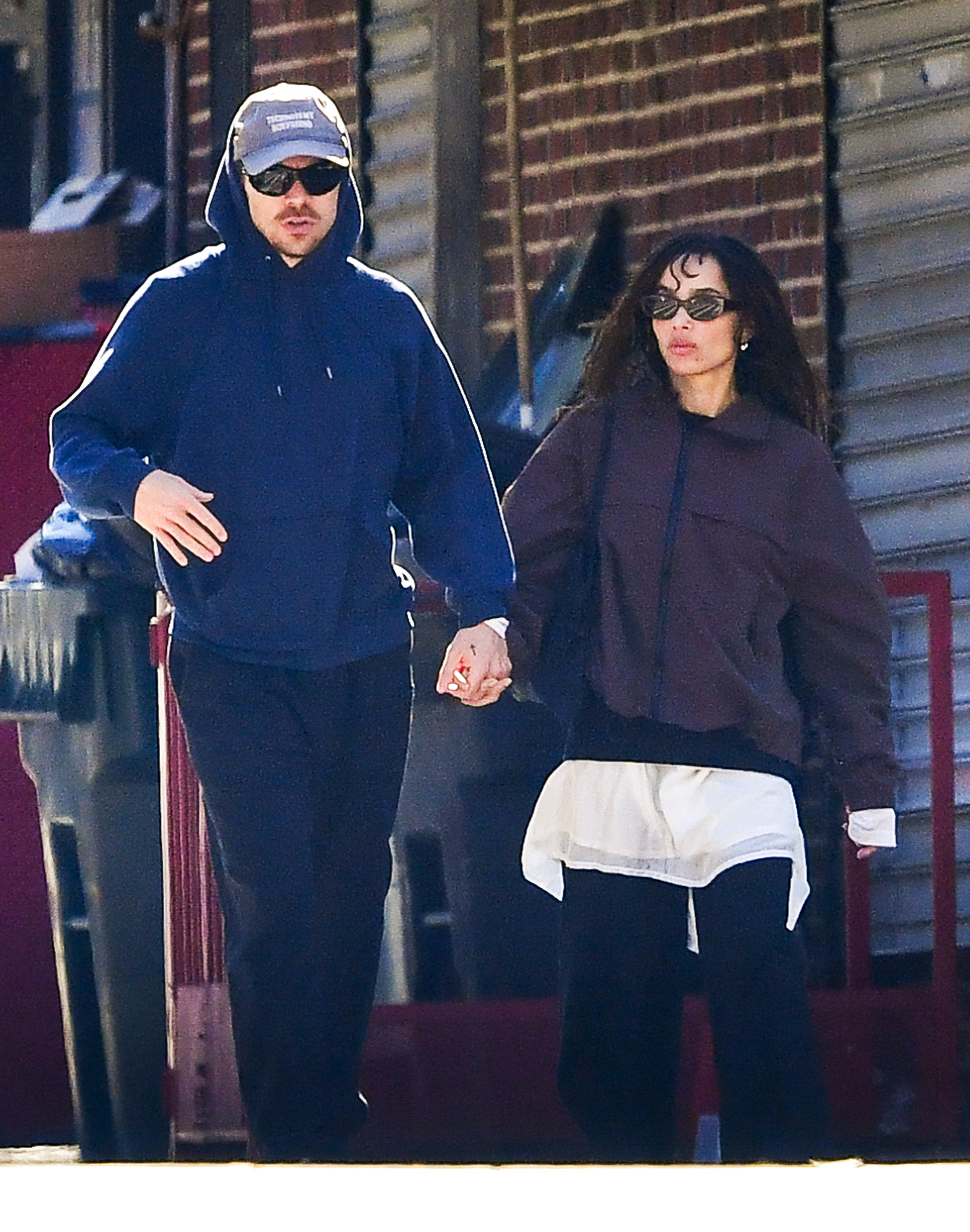 Harry Styles and Zoe Kravitz hold hands on a stroll in New York City. Zoe wore a brown jacket, a white minidress, and black pants.