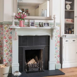 Living room with pink floral wallpaper and white fireplace