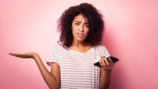 Young woman with mobile phone looking confused