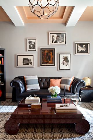 Living room with grey walls, black leather sofa, brown gloss coffee table and gallery wall