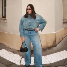 Woman wearing plus size jeans with matching denim shirt, standing on Paris street.