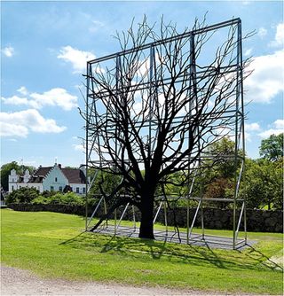 Large piece of scaffolding in a park, with a flat tree structure against it
